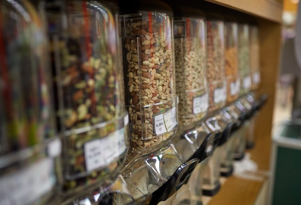 sale and eco food concept - row of jars with nuts and seeds at grocery store